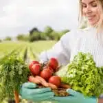 organik tarım çiftliğin de elinde havuç domates ve marul tutan kadın